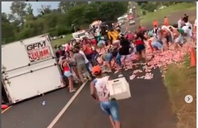 Carreta carregada de refrigerantes tomba na BR-153; vídeos mostram carga espalhada na pista sendo levada por populares 