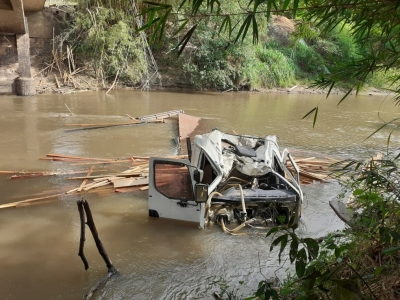 Caminhão carregado com madeira cai em rio e deixa motorista ferido na região